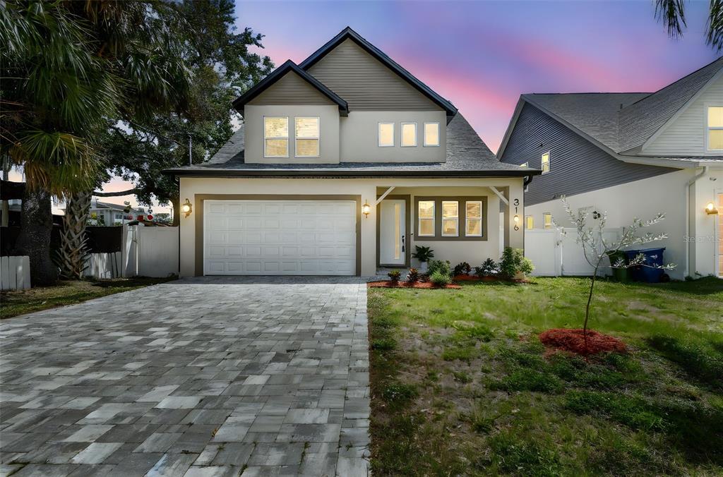 A two-story house with a paved driveway, white garage door, and a small front yard — 3106 W CHEROKEE AVENUE, TAMPA, FL