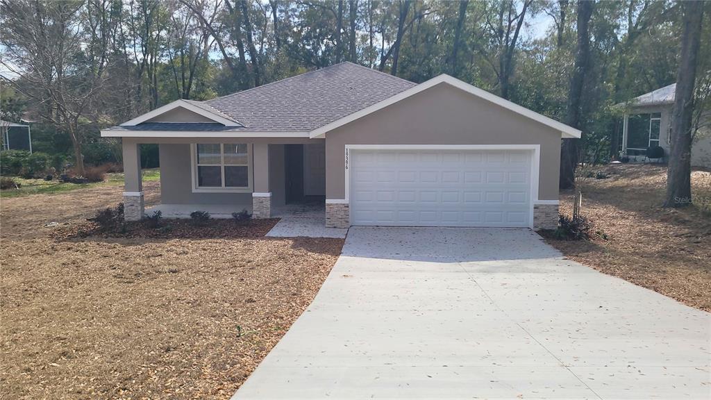 A single-story house with a white garage door, tan exterior, and a covered front porch — 19396 SW 101ST PLACE ROAD, DUNNELLON, FL