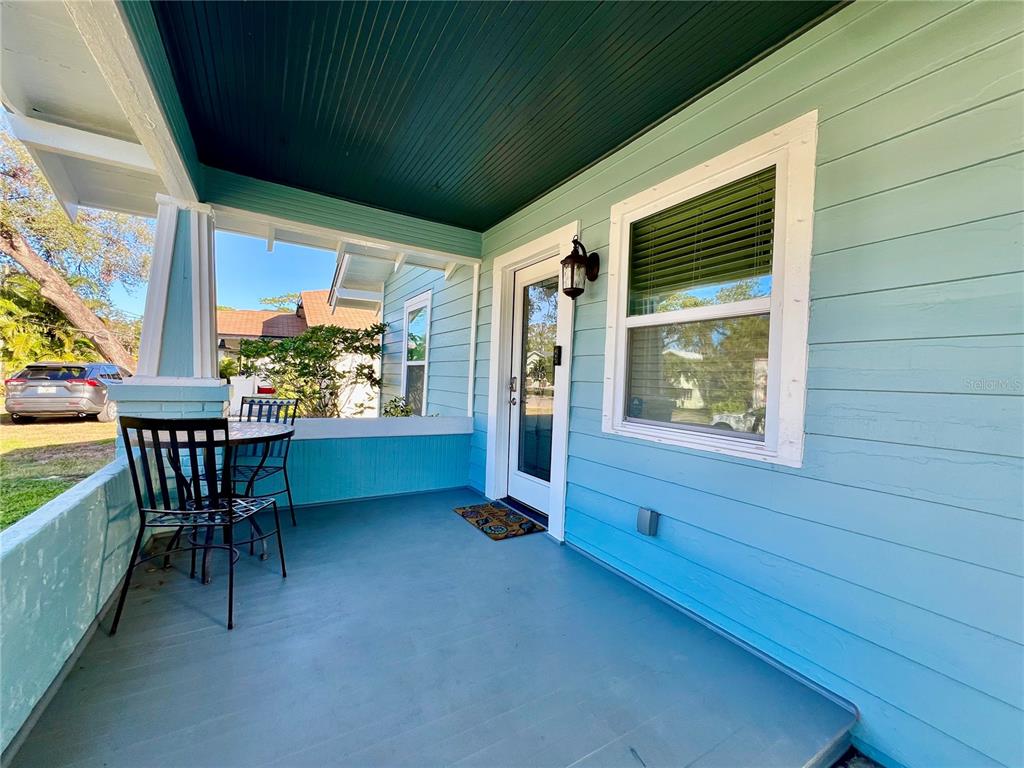A light blue house features a covered front porch with a table and chairs — 5907 N OLA AVENUE, TAMPA, FL