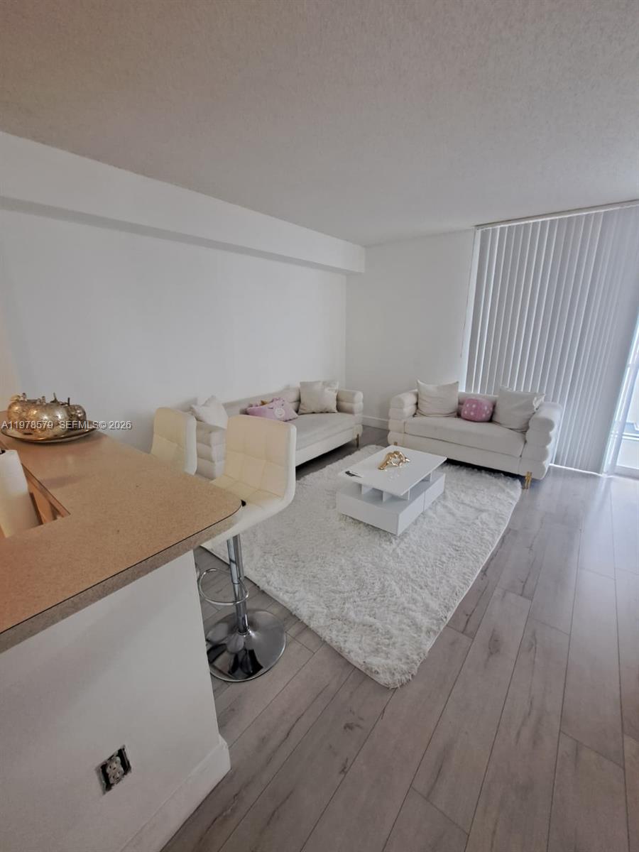 A living room features white sofas, a coffee table, a rug, and bar stools — 5077 NW 7th St # 912, Miami FL 33126, MIAMI, FL
