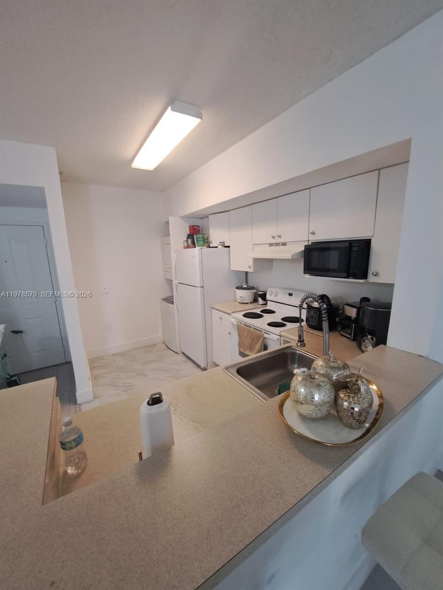 A kitchen features white cabinets, a white stove, a microwave, and a breakfast bar — 5077 NW 7th St # 912, Miami FL 33126, MIAMI, FL
