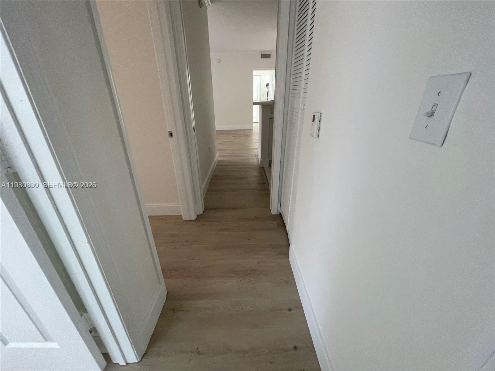 A hallway with light wood-look flooring leads toward an open living area — 6821 SW 44th St # 301, Miami FL 33155, MIAMI, FL
