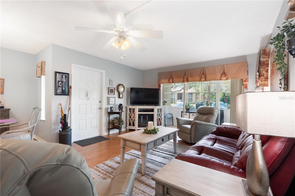 A living room features a red leather sofa, a coffee table, and a ceiling fan — 12218 FOX CHASE DRIVE UNIT C1, HUDSON, FL