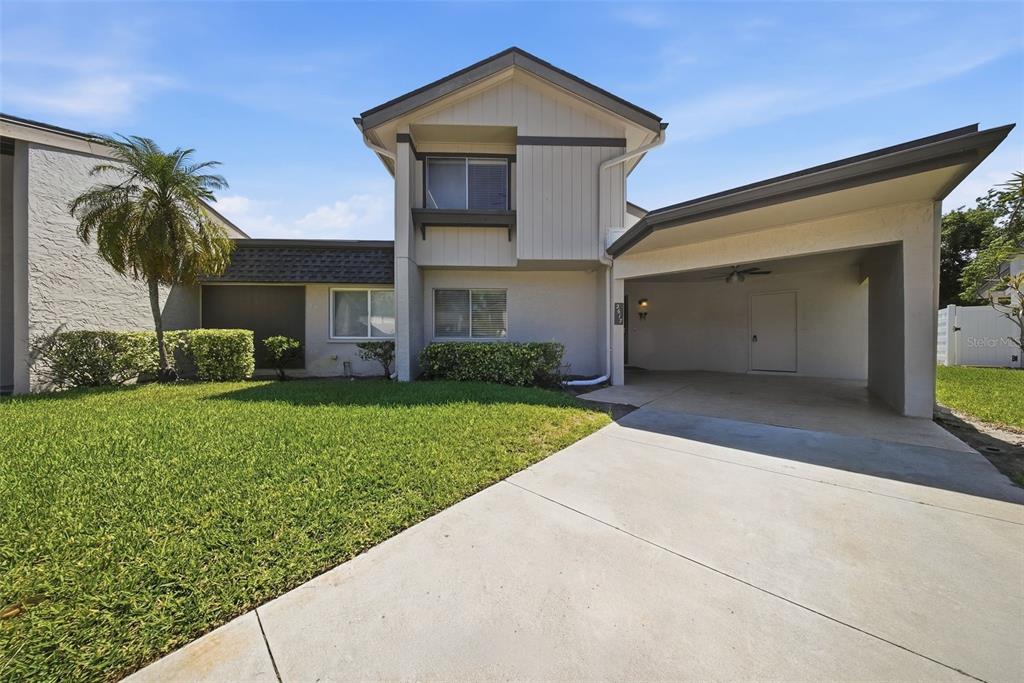 A two-story house features a concrete driveway, a covered carport, and a front lawn — 2617 BARKSDALE COURT, CLEARWATER, FL