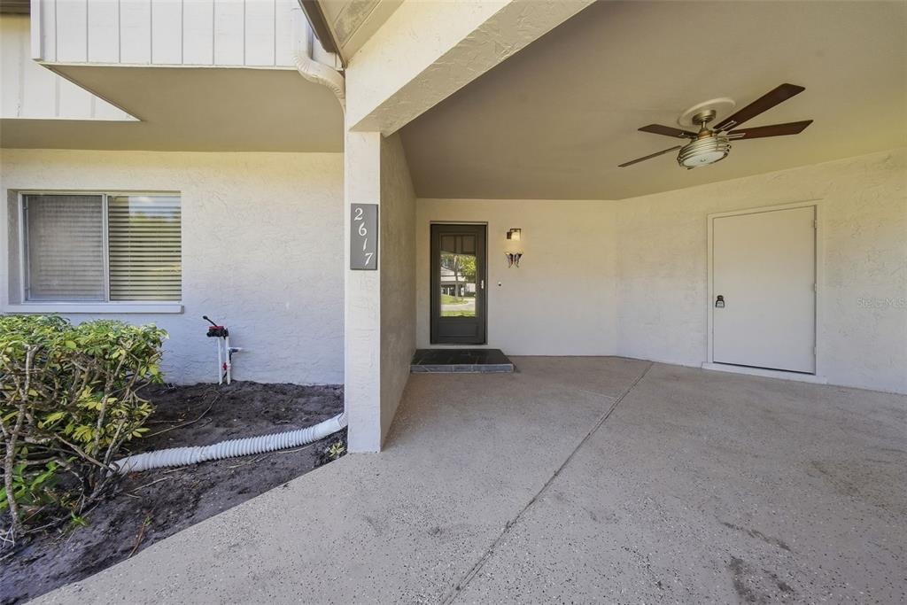 The exterior view shows a covered entryway with a front door, a side door, and a ceiling fan — 2617 BARKSDALE COURT, CLEARWATER, FL