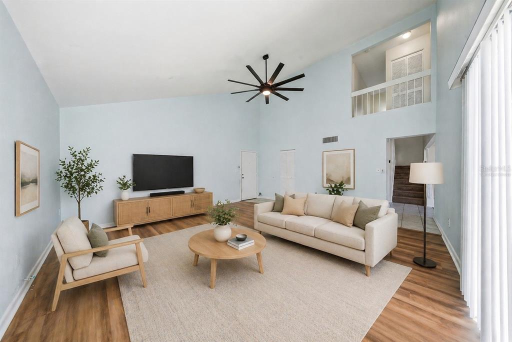 A living room with light blue walls, vaulted ceilings, a ceiling fan, and wood-look flooring — 2617 BARKSDALE COURT, CLEARWATER, FL