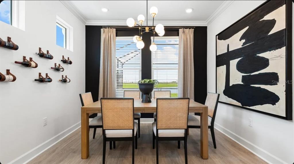 A dining room features a wooden table, cane-back chairs, a wine rack wall, and modern lighting — 7649 MOONBEAM AVENUE, SARASOTA, FL