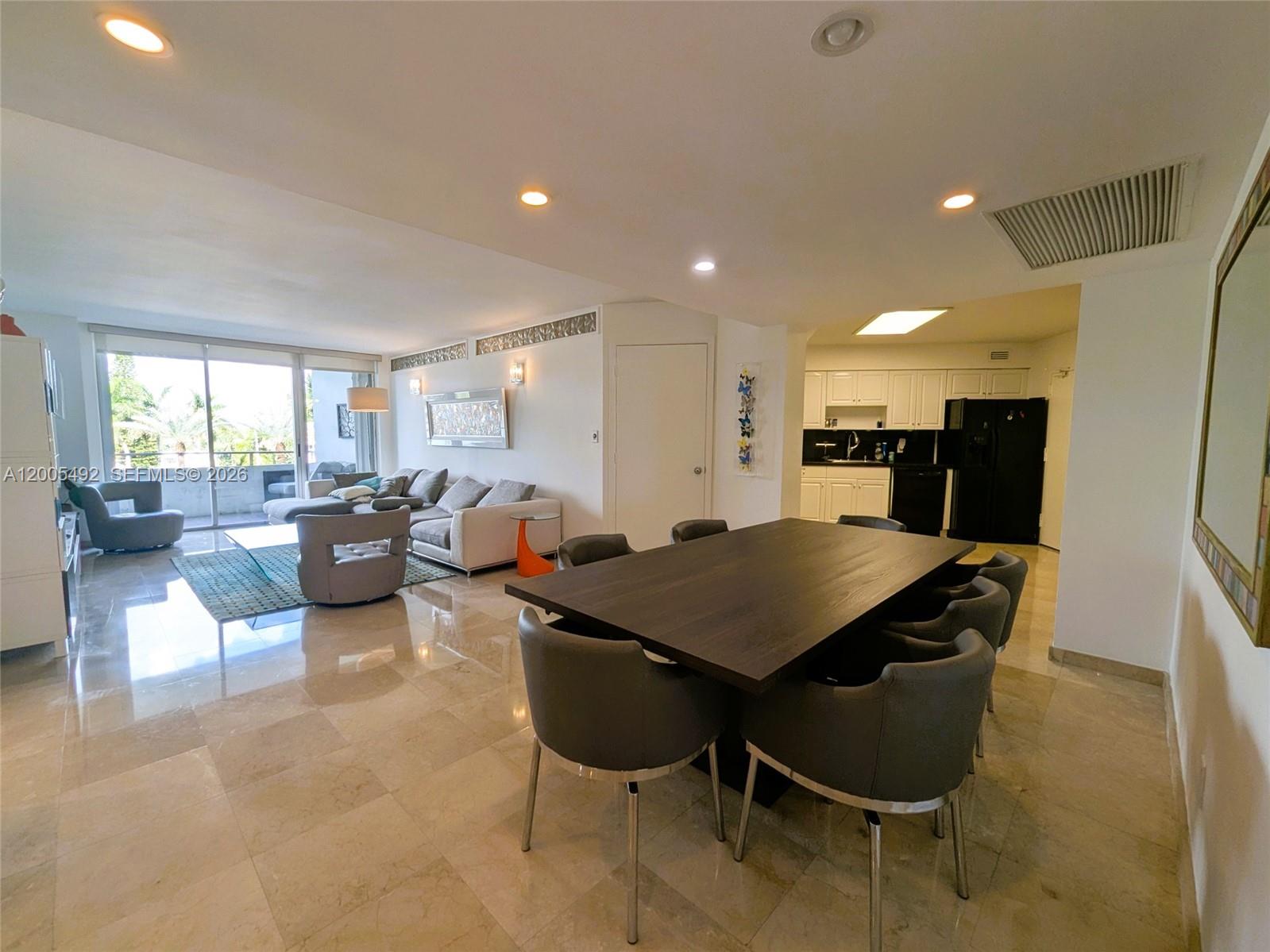 An open-concept living and dining area features tile flooring, a dark wood table, and kitchen — 5161 Collins Ave # 518, Miami Beach FL 33140, MIAMI BEACH, FL