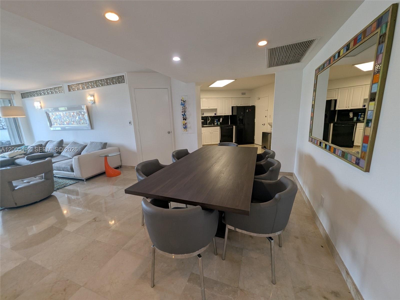 A dining area with a dark wood table and gray chairs sits beside a living room — 5161 Collins Ave # 518, Miami Beach FL 33140, MIAMI BEACH, FL