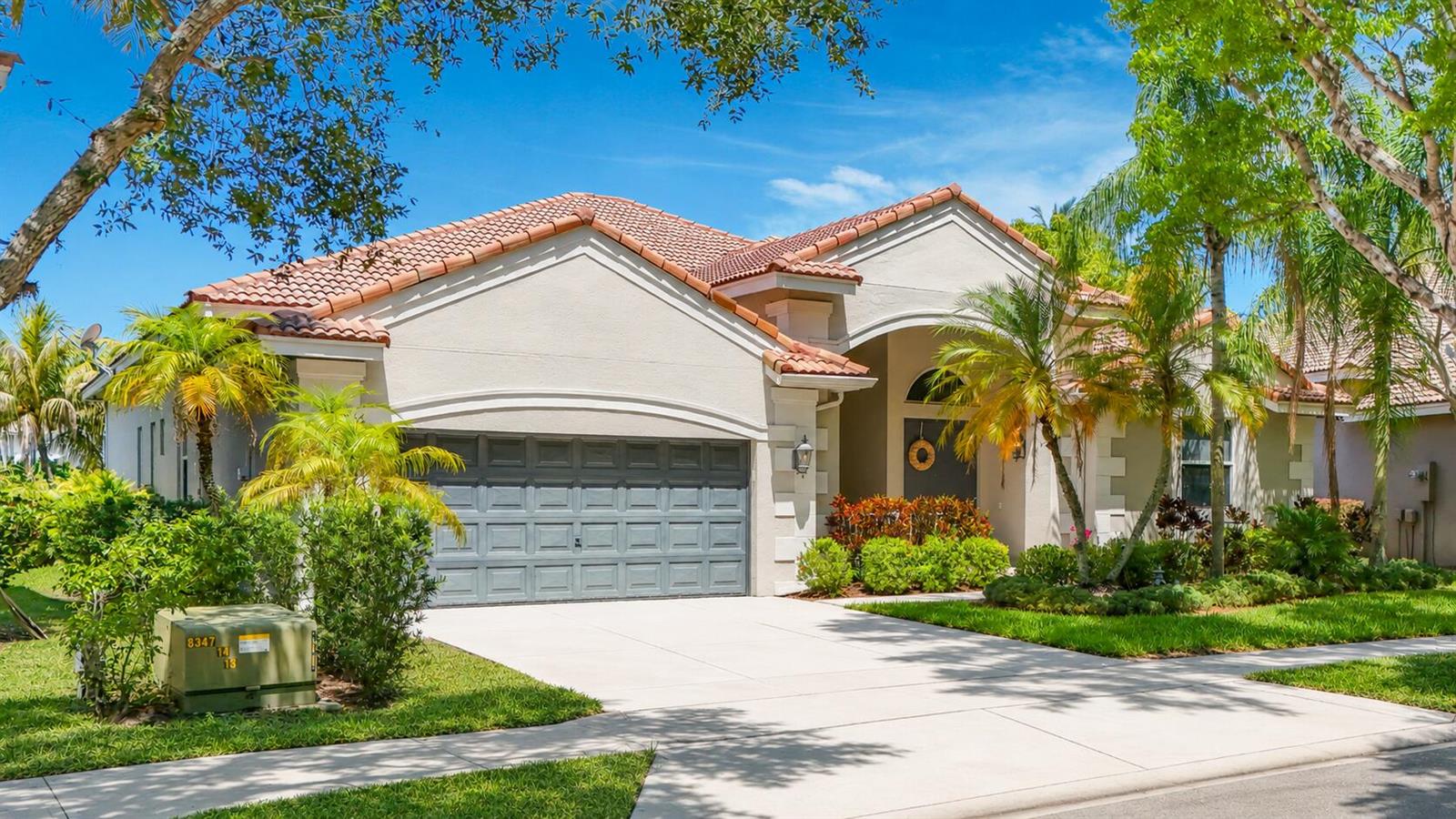 A single-story house with a tile roof, gray garage door, and palm trees in the yard — 3836 Heron Ridge Lane, Weston FL 33331, WESTON, FL