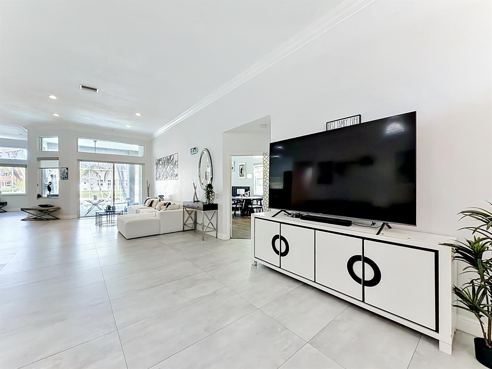 A bright living room features large white floor tiles, a modern media console, and sliding doors — 3836 Heron Ridge Lane, Weston FL 33331, WESTON, FL