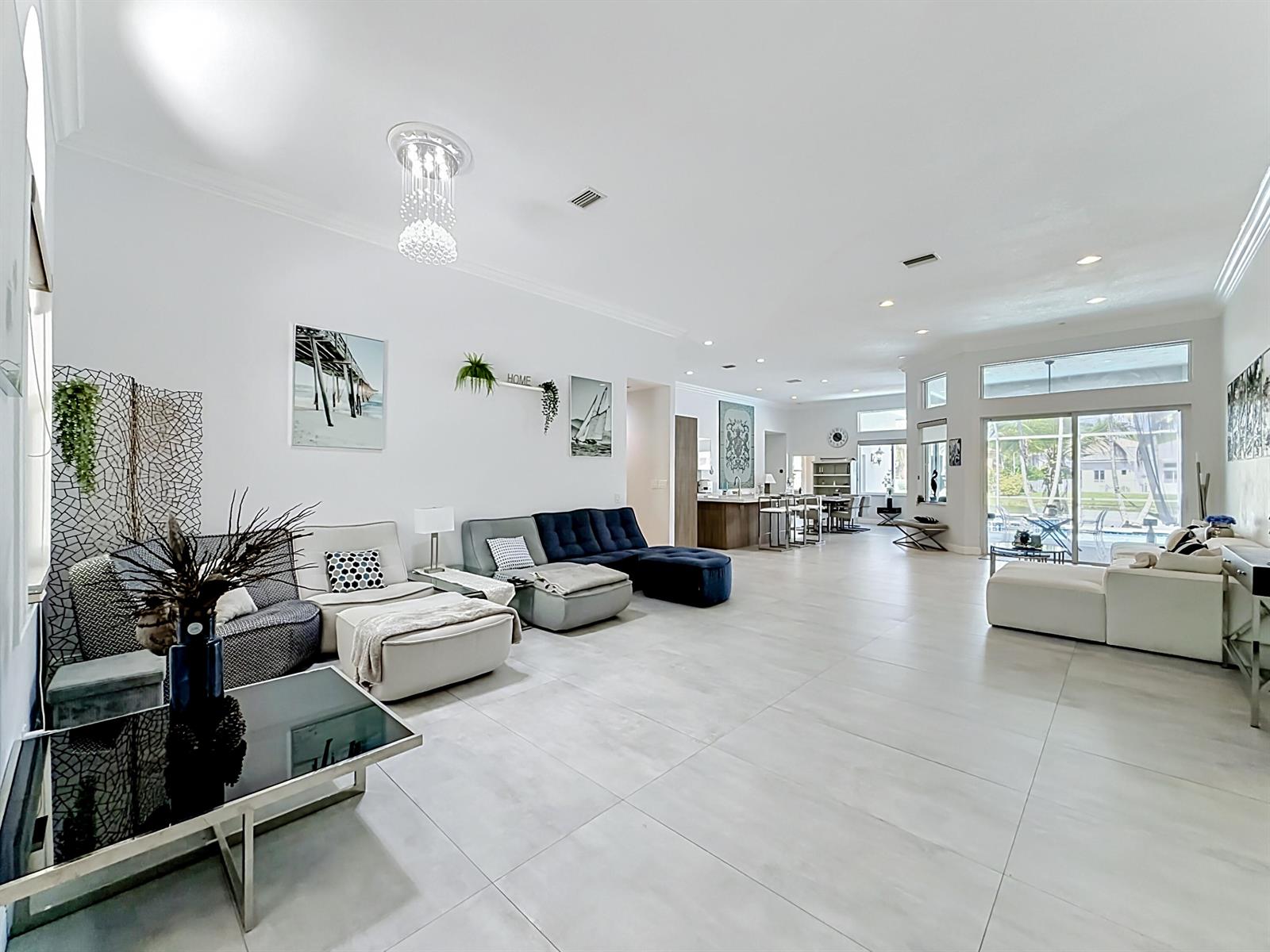 A spacious, open-concept living room features light tile flooring, modern furniture, and large sliding glass doors — 3836 Heron Ridge Lane, Weston FL 33331, WESTON, FL