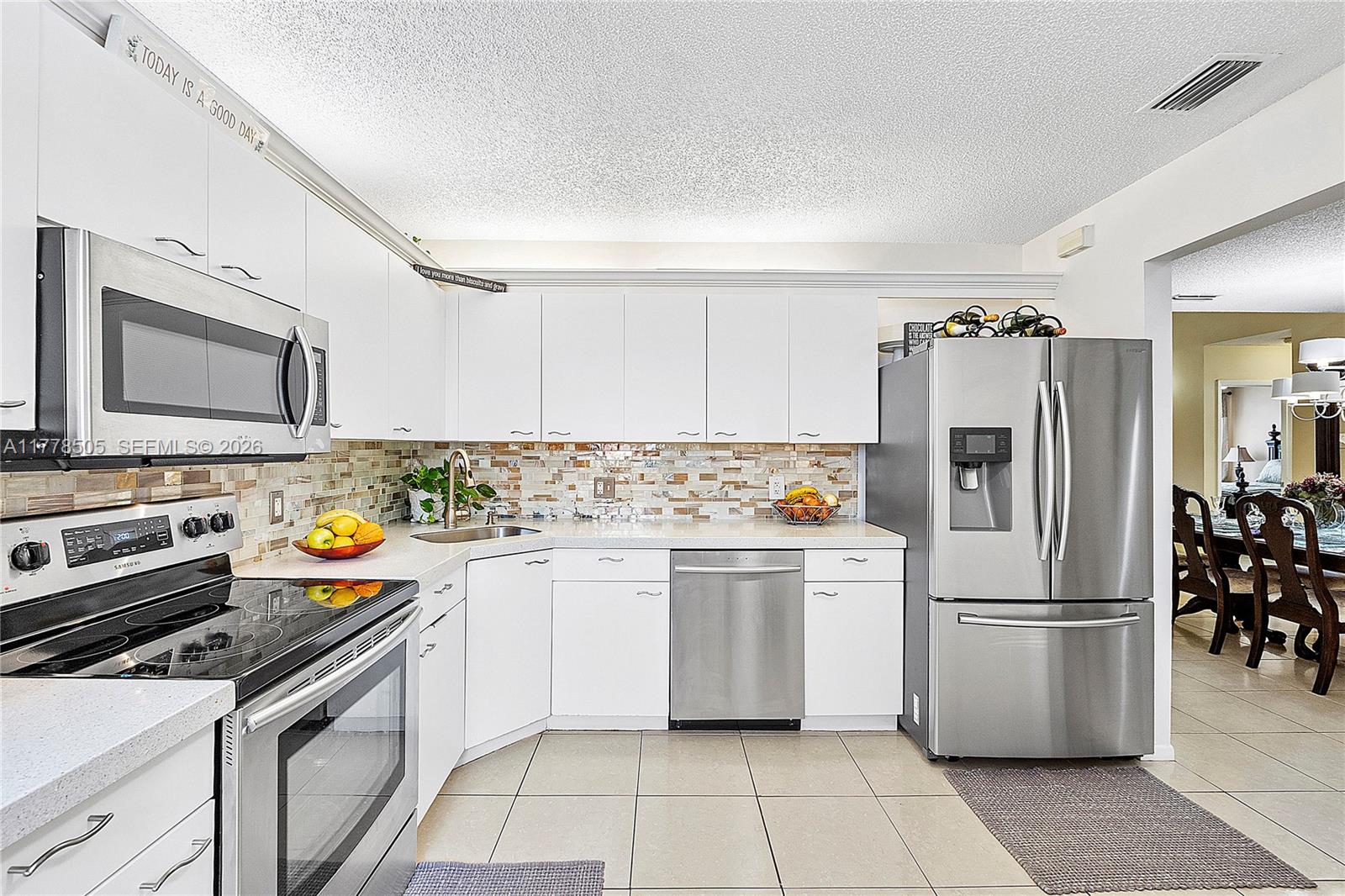A screened-in balcony features a wooden table, two chairs, a potted plant, and tile flooring — 4101 E Coral Tree Cir # 313, Coconut Creek FL 33073, COCONUT CREEK, FL