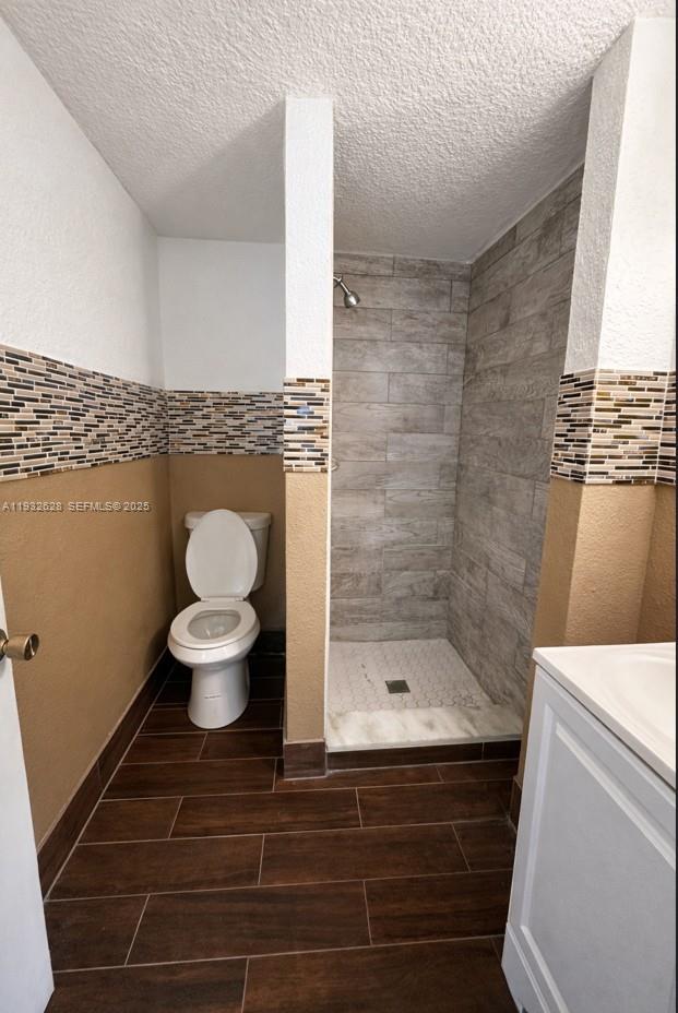A bathroom features a walk-in shower with wood-look tile, a toilet, and brown wall paint — 14405 NE 5th Ave # B, Miami FL 33161, MIAMI, FL