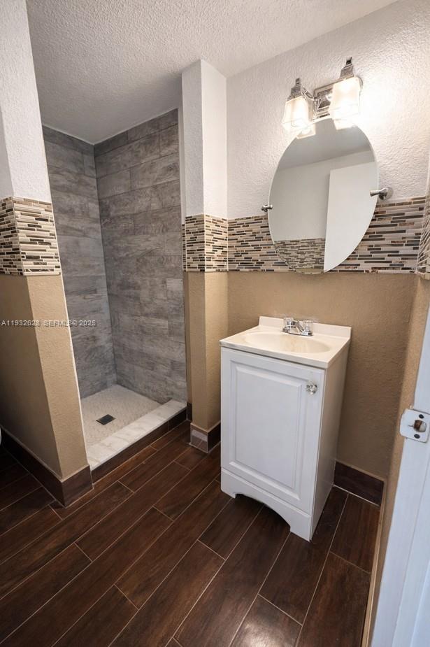 A bathroom features a walk-in shower with gray tile, a white vanity, and wood-look flooring — 14405 NE 5th Ave # B, Miami FL 33161, MIAMI, FL