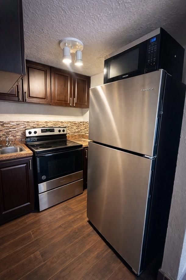 A kitchen features dark wood cabinets, stainless steel appliances, and a mosaic tile backsplash — 14405 NE 5th Ave # B, Miami FL 33161, MIAMI, FL