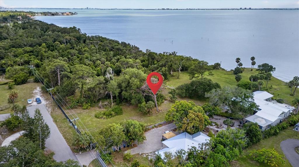 An aerial view shows a wooded waterfront lot with a red location pin marker — 8258 LONGBAY BLVD, SARASOTA, FL