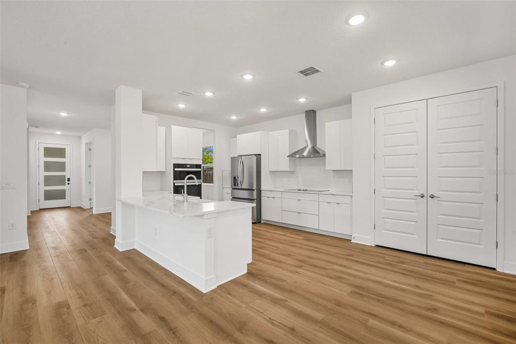 A modern kitchen features white cabinetry, stainless steel appliances, a marble island, and wood flooring — 3108 W BALLAST POINT BOULEVARD, TAMPA, FL