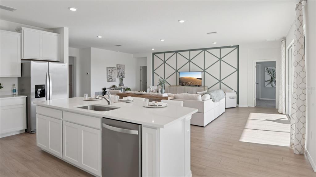 A modern open-concept kitchen and living room featuring white cabinetry, a large island, and wood-look flooring — 1743 NW 127TH DRIVE, NEWBERRY, FL