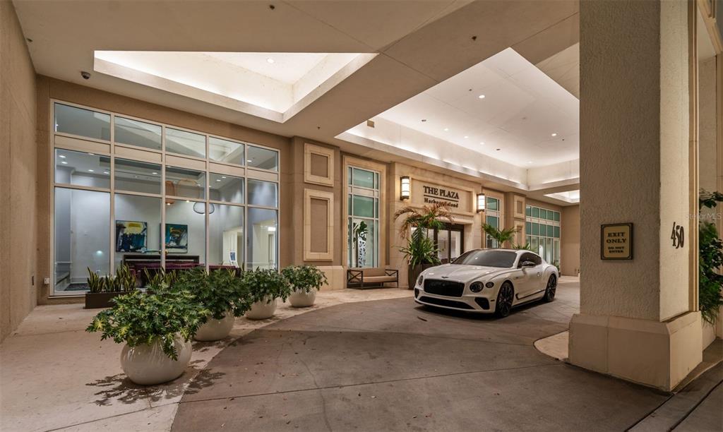 A white luxury car is parked under the covered entrance of a modern apartment building — 450 KNIGHTS RUN AVENUE UNIT 2004, TAMPA, FL