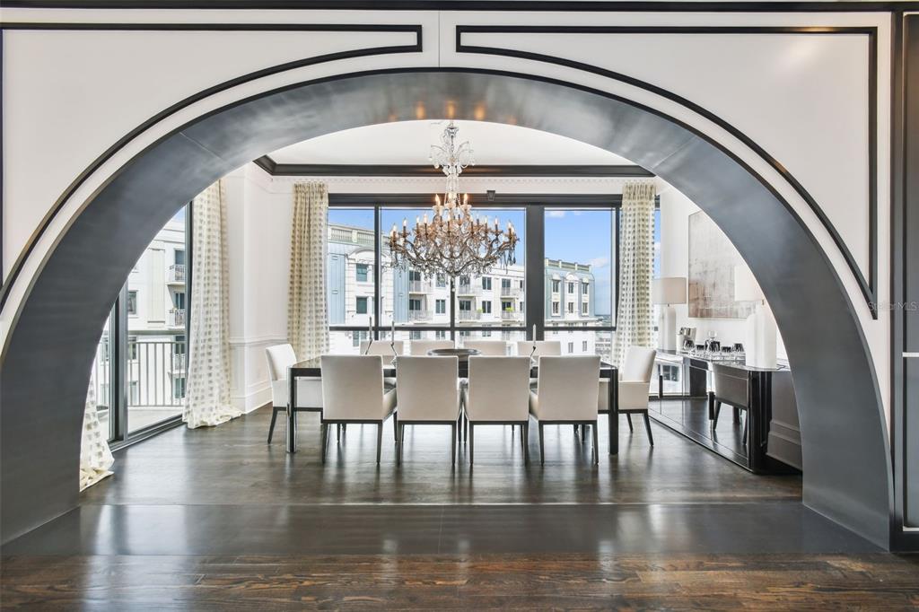 A dining room with a large chandelier is framed by a dark, arched architectural opening — 450 KNIGHTS RUN AVENUE UNIT 2004, TAMPA, FL