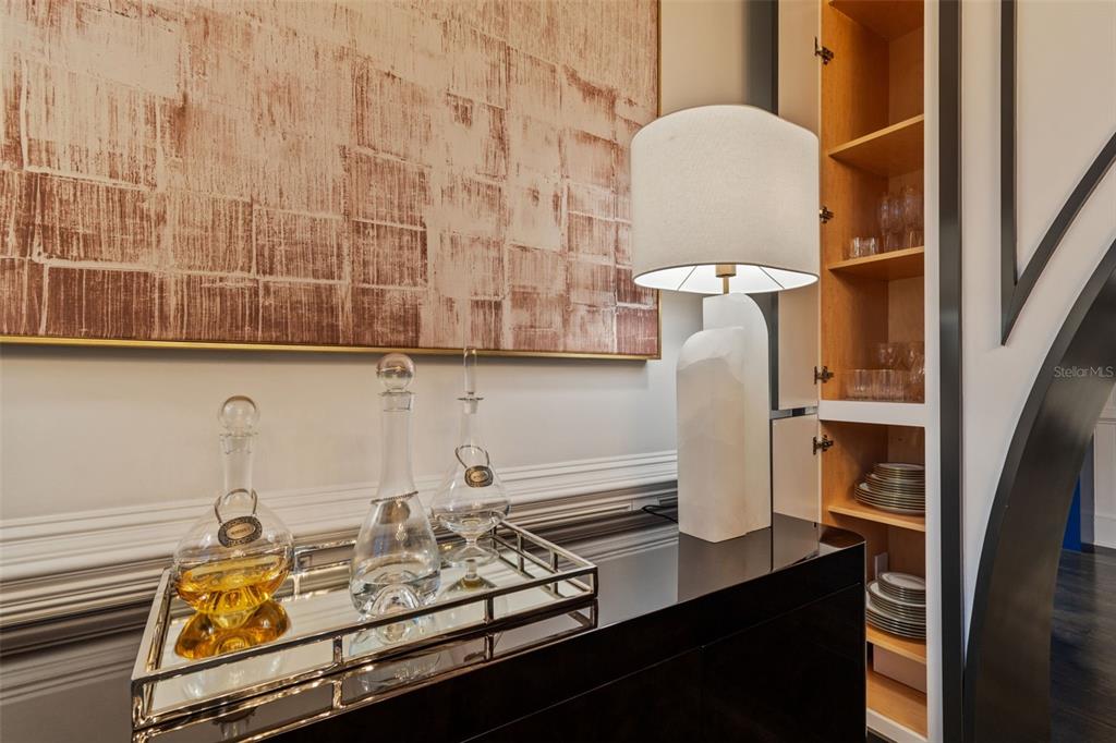 A black console table holds a lamp and glass decanters beneath a large textured painting — 450 KNIGHTS RUN AVENUE UNIT 2004, TAMPA, FL