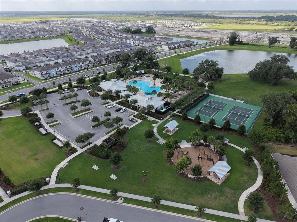 An aerial view shows a community clubhouse with a pool, tennis courts, and a playground — 1831 BRIGHT SKY DRIVE, KISSIMMEE, FL