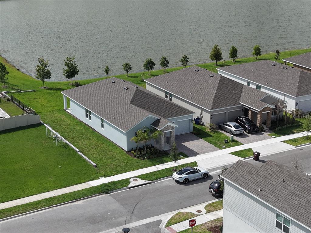 An aerial view shows two suburban houses with driveways situated along a lakefront — 1831 BRIGHT SKY DRIVE, KISSIMMEE, FL