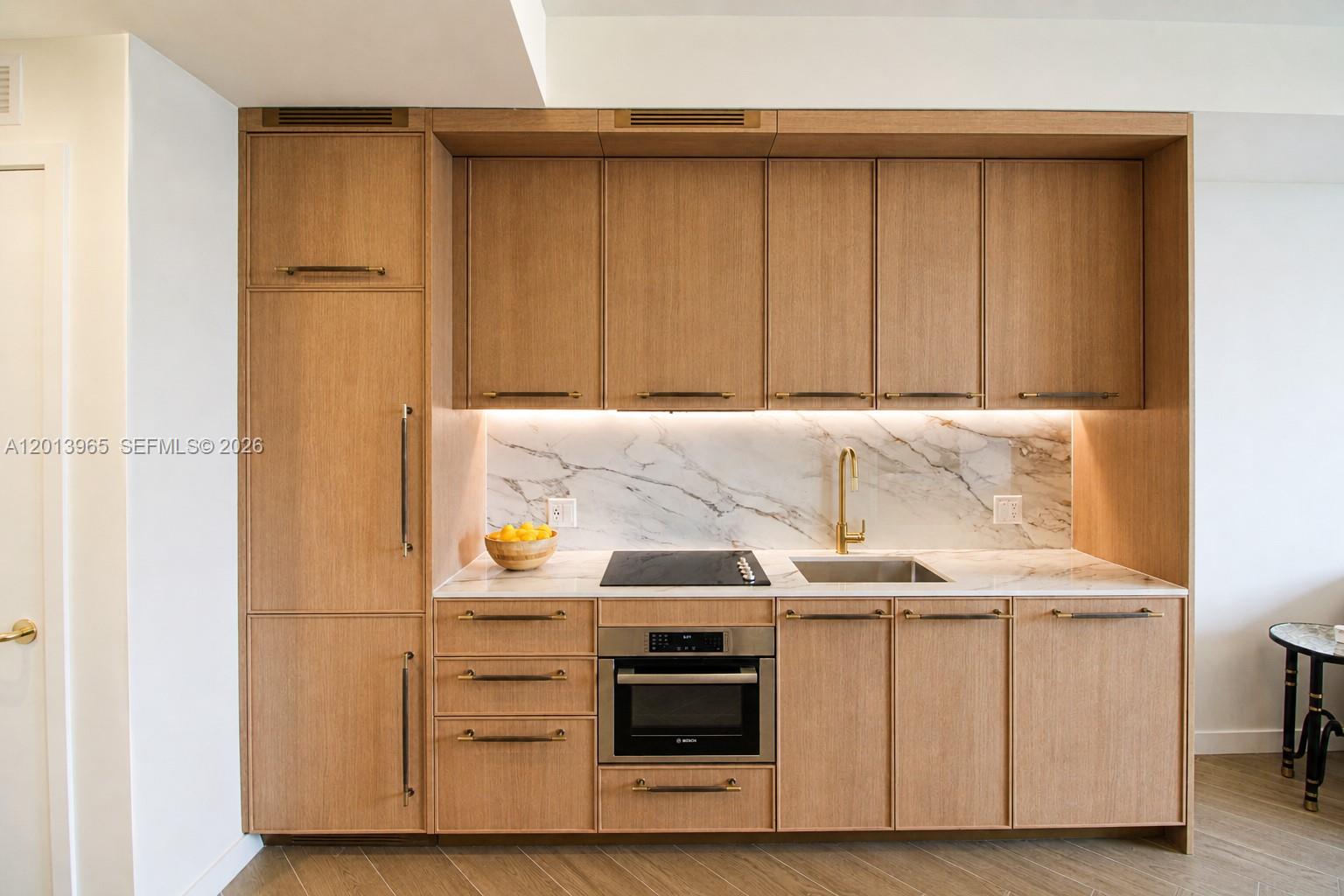 A modern kitchen features light wood cabinetry, a marble backsplash, and stainless steel appliances — 2700 NW 2nd Ave # 202, Miami FL 33127, MIAMI, FL