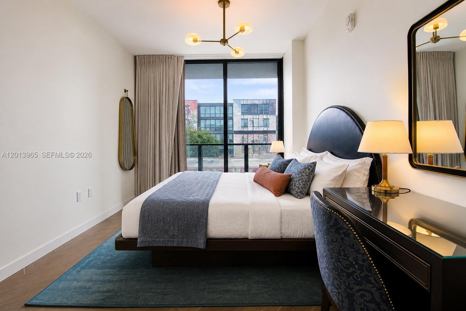 A modern bedroom features a platform bed, blue area rug, and a view of buildings — 2700 NW 2nd Ave # 202, Miami FL 33127, MIAMI, FL
