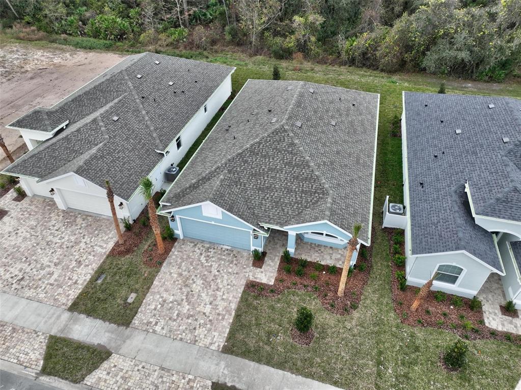 An aerial view shows three suburban houses with paved driveways and shingled roofs — 49 MATANZAS COVE DRIVE, PALM COAST, FL