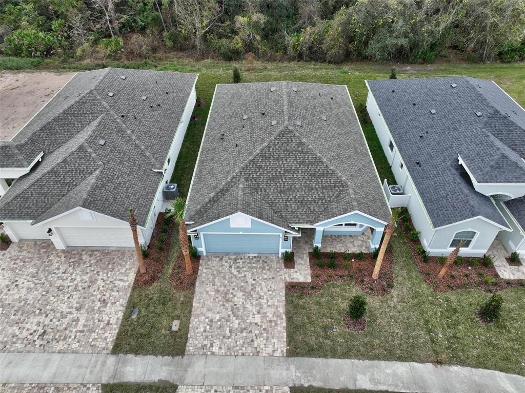 An aerial view shows three suburban houses with paved driveways and shingled roofs — 49 MATANZAS COVE DRIVE, PALM COAST, FL