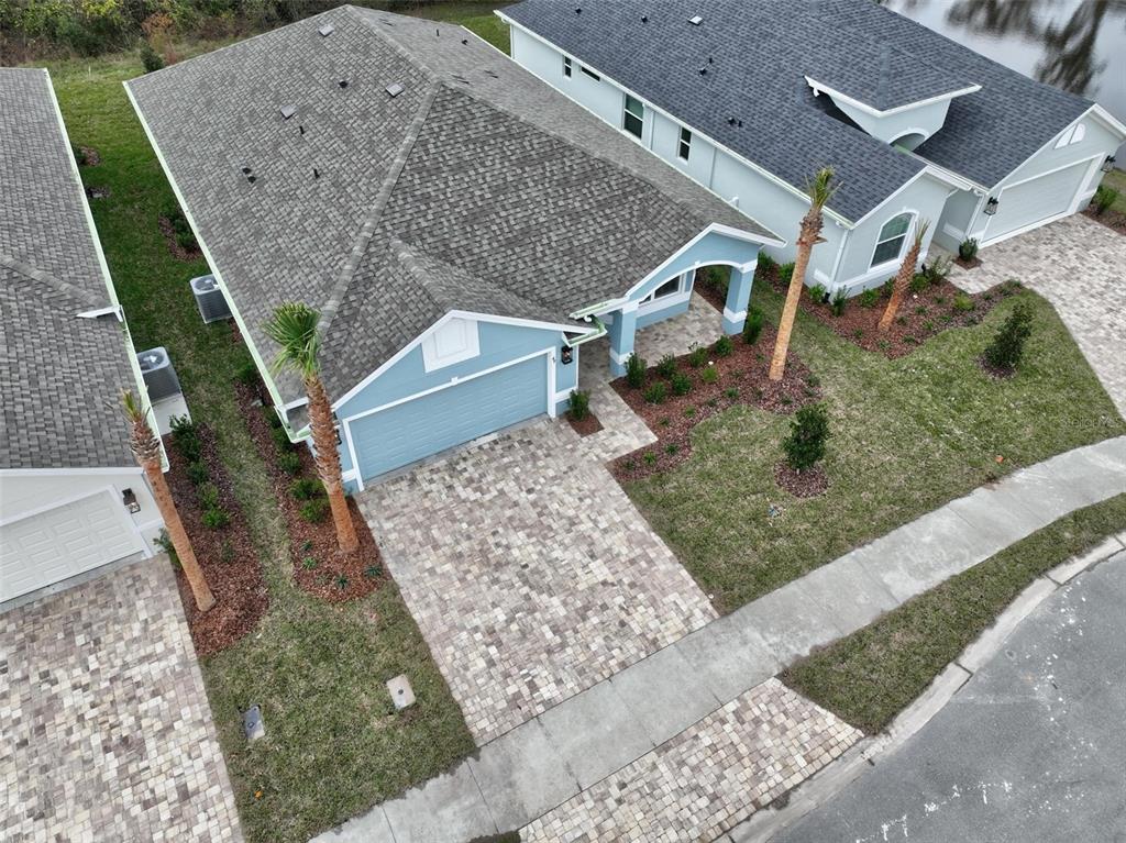 An aerial view shows a blue house with a paver driveway and a shingled roof — 49 MATANZAS COVE DRIVE, PALM COAST, FL
