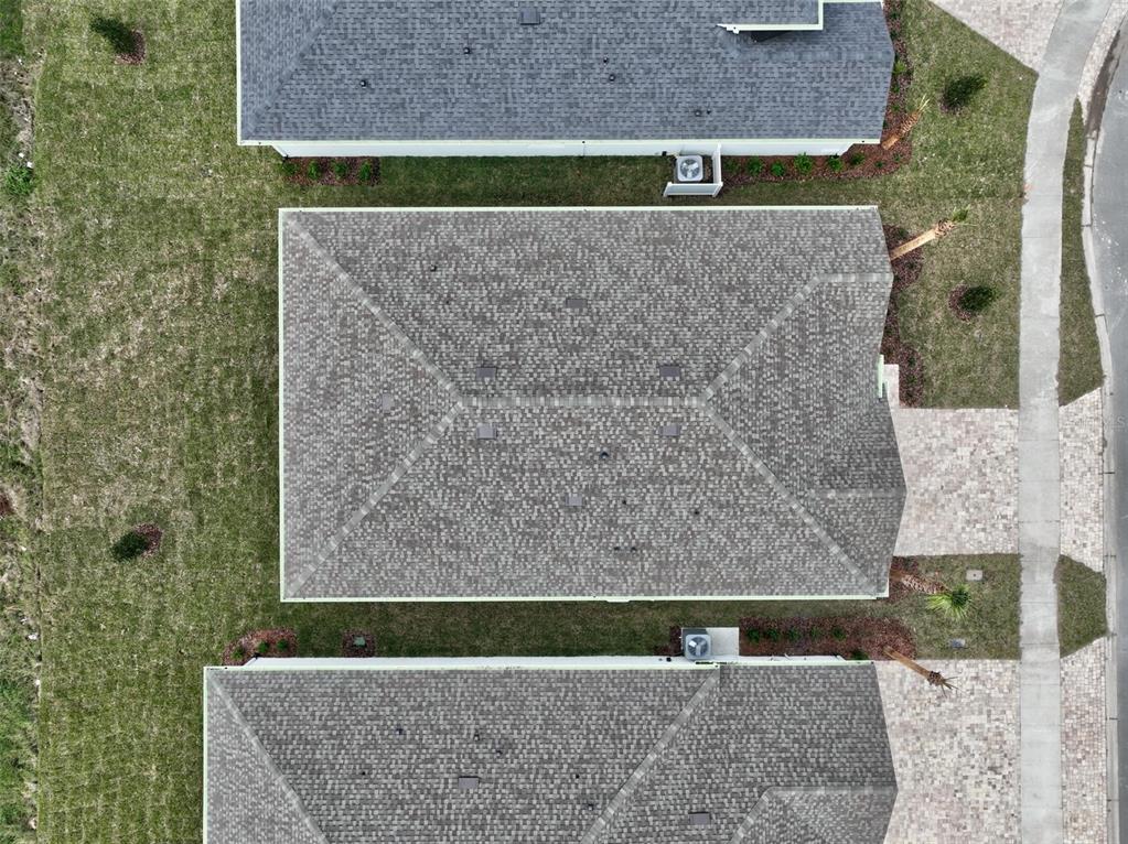 An aerial view shows the roofs of three adjacent suburban houses with paved driveways and lawns — 49 MATANZAS COVE DRIVE, PALM COAST, FL