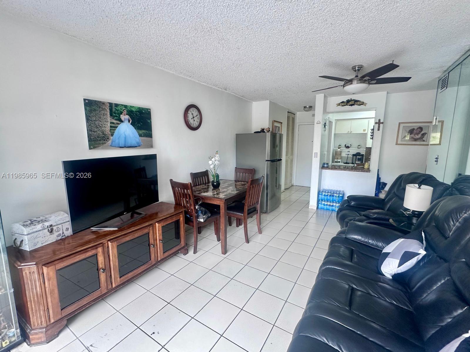 This living and dining area features tile flooring, a television console, and black leather furniture — 2385 NW 11th St # B16, Miami FL 33125, MIAMI, FL
