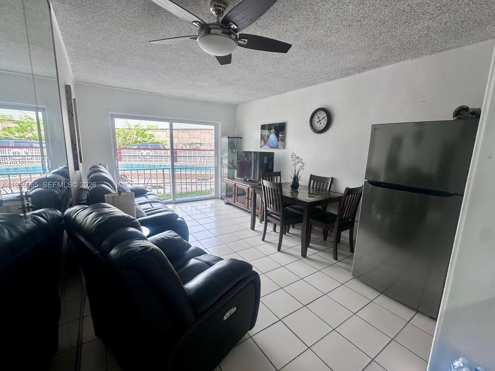 A living and dining area features tile floors, a ceiling fan, and a sliding glass door — 2385 NW 11th St # B16, Miami FL 33125, MIAMI, FL