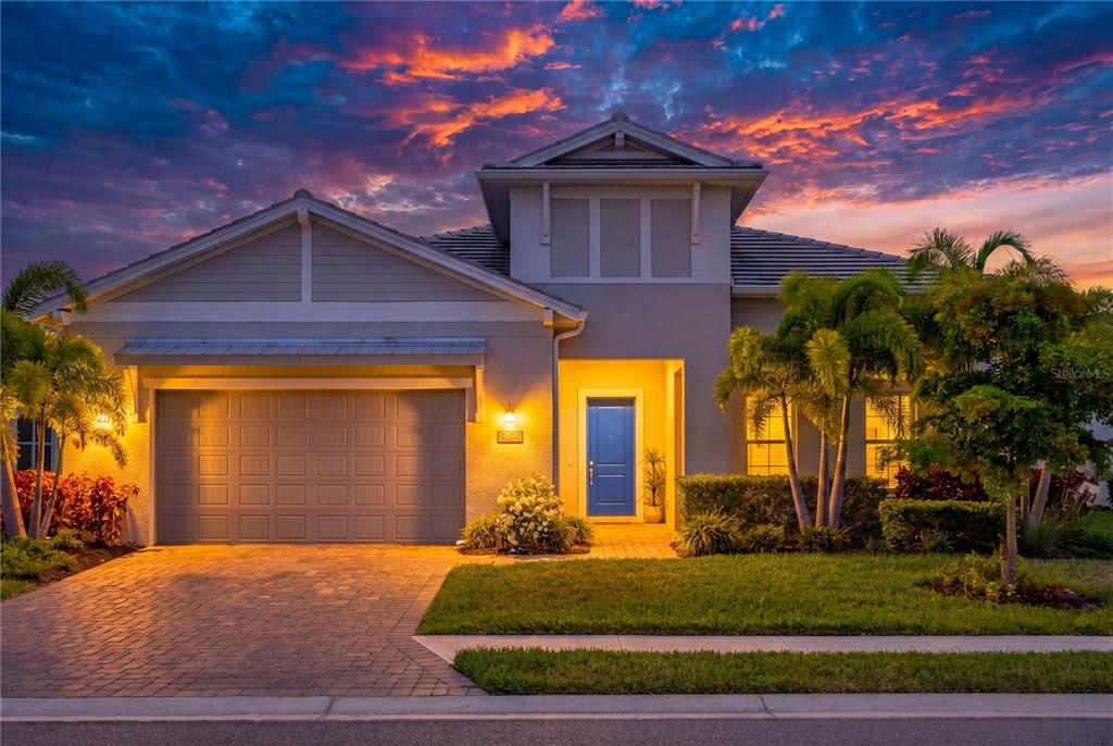 A single-story house with a blue garage door, a front entrance, and palm trees — 8154 REDONDA LOOP, LAKEWOOD RANCH, FL