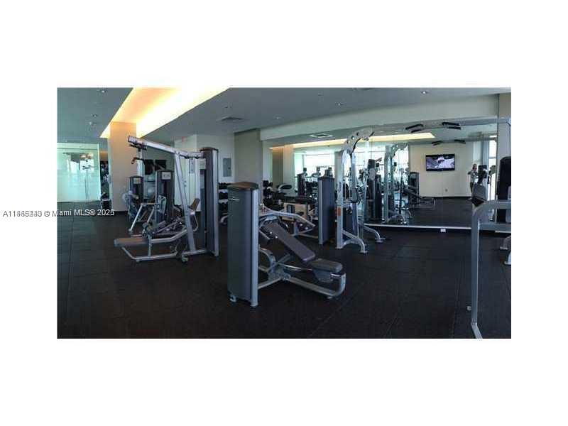 A fitness center features various weight machines, rubber flooring, and large wall-to-wall mirrors — 3301 NE 1st Ave # H2408, Miami FL 33137, MIAMI, FL