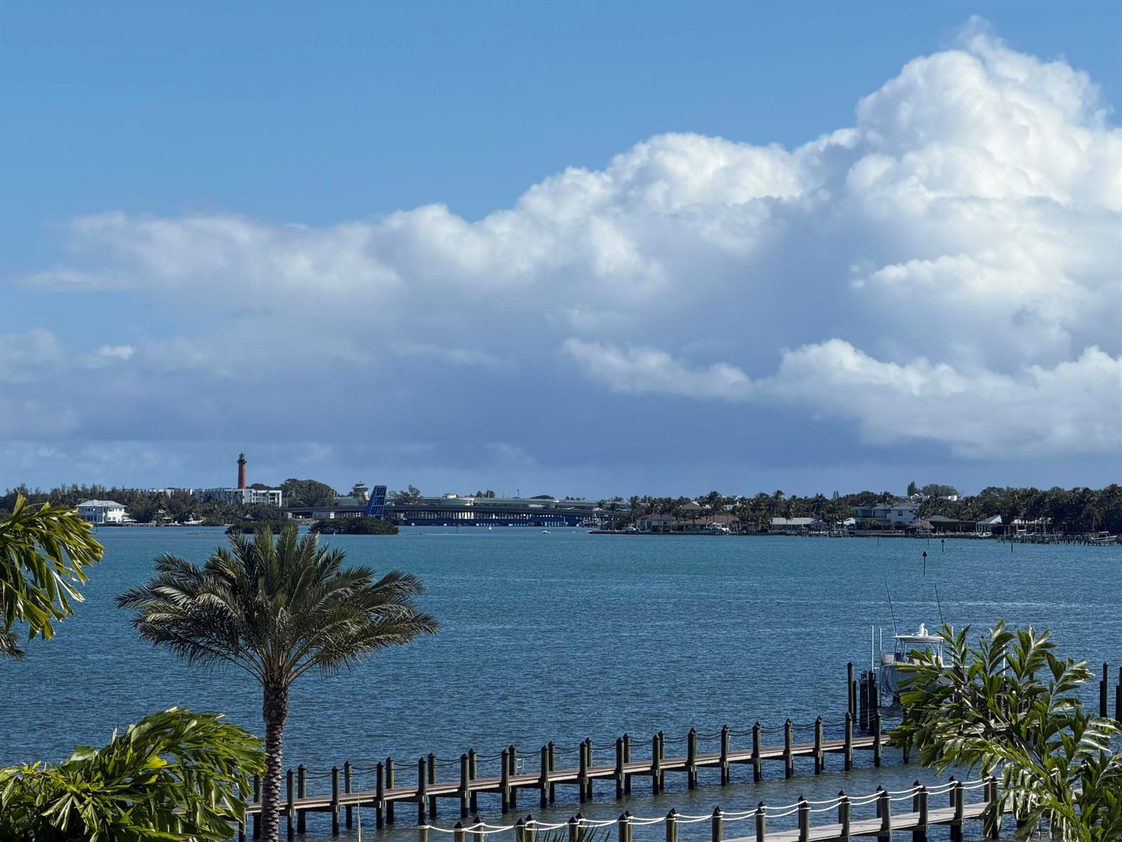 A view of a waterway with a dock, palm trees, and a distant lighthouse — 5270 Pennock Point Road, Jupiter FL 33458, JUPITER, FL