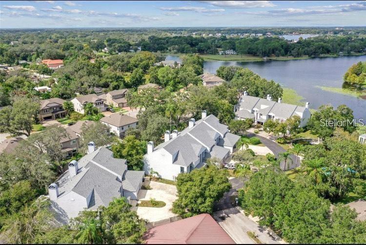 An aerial view shows several multi-story residential buildings surrounded by trees near a lake — 9726 TIFFANY OAKS LANE UNIT 9726, TAMPA, FL