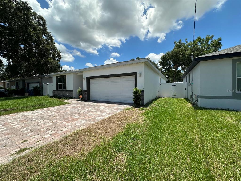 A single-story house with a white exterior, a paved driveway, and a two-car garage — 117 W MURPHY STREET, DAVENPORT, FL