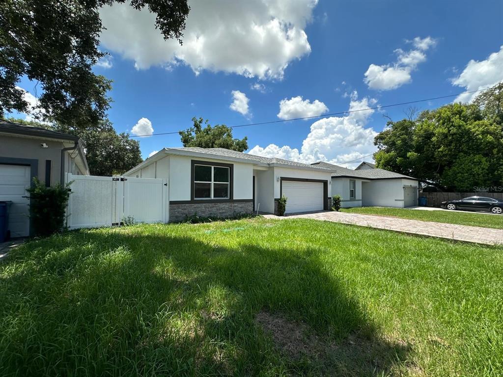 A single-story house with a white exterior, stone accents, and a paved driveway — 117 W MURPHY STREET, DAVENPORT, FL
