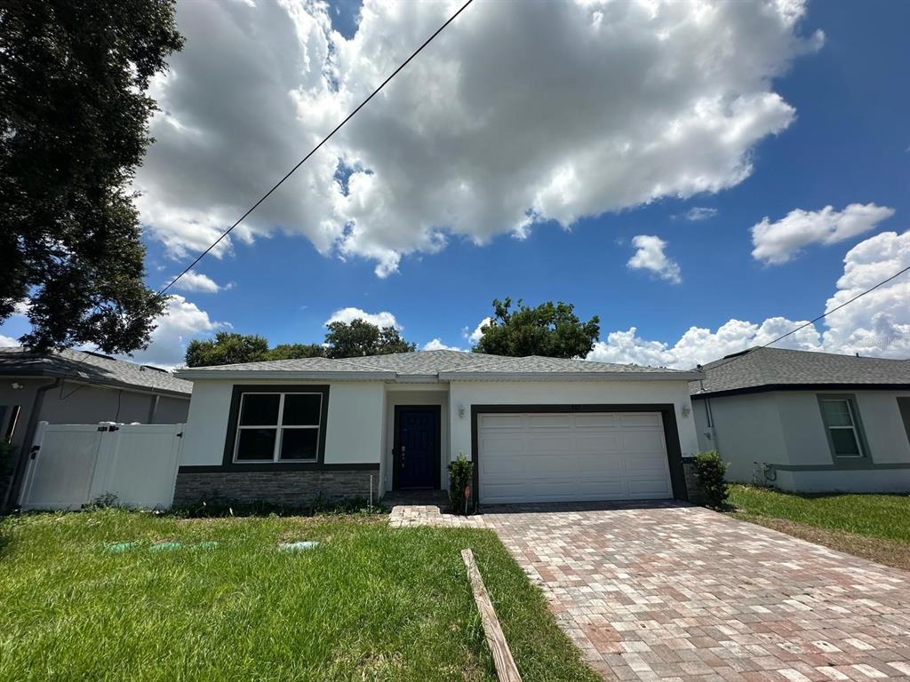 A single-story house with a white exterior, stone base, and a paved driveway — 117 W MURPHY STREET, DAVENPORT, FL