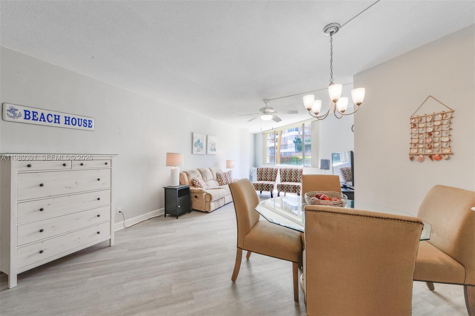 This living and dining area features light wood-look flooring, a glass table, and coastal decor — 1936 S Ocean Dr # 2D, Hallandale Beach FL 33009, HALLANDALE BEACH, FL
