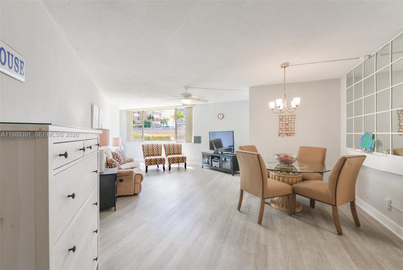 This living and dining area features light wood-look flooring, a glass-topped table, and large windows — 1936 S Ocean Dr # 2D, Hallandale Beach FL 33009, HALLANDALE BEACH, FL