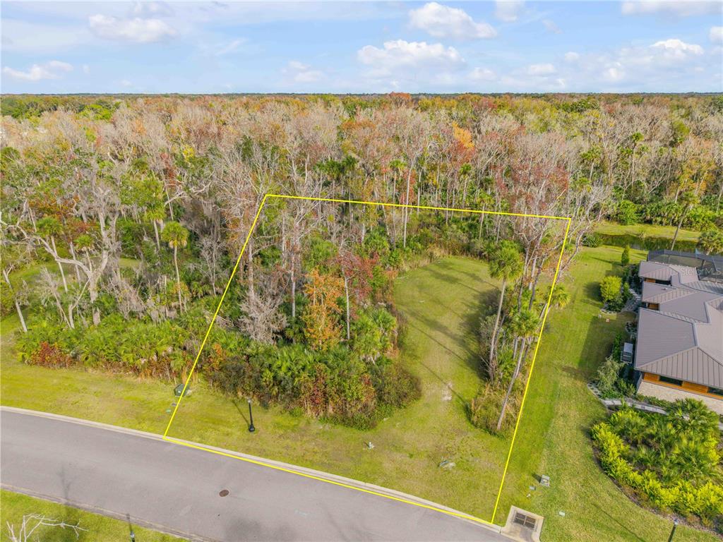 An aerial view shows a vacant, partially wooded residential lot outlined in yellow — 2307 LEGACY LANE, NEW SMYRNA BEACH, FL