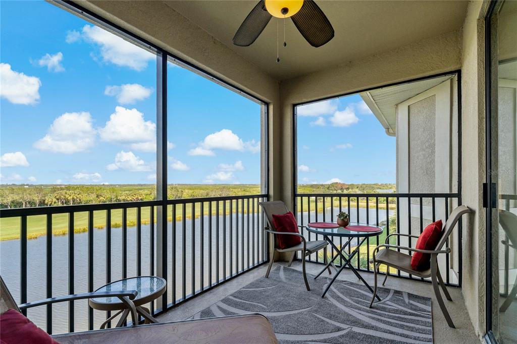 A screened-in balcony features a ceiling fan, outdoor furniture, and a view of a lake — 7015 RIVER HAMMOCK DRIVE UNIT 405, BRADENTON, FL