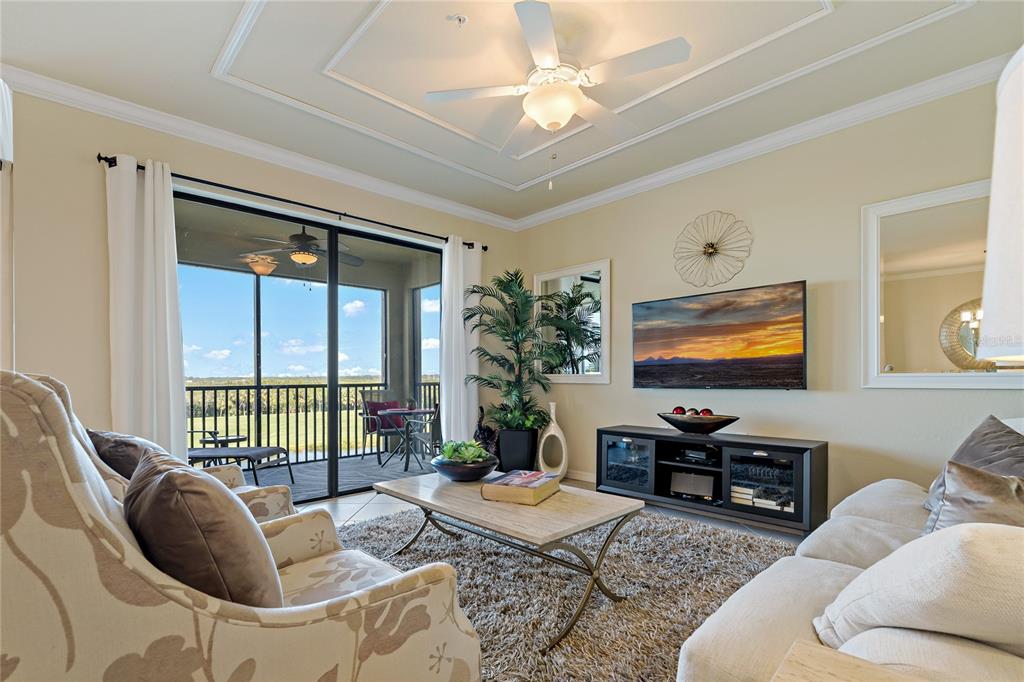 A living room features a ceiling fan, a television, a coffee table, and a balcony — 7015 RIVER HAMMOCK DRIVE UNIT 405, BRADENTON, FL
