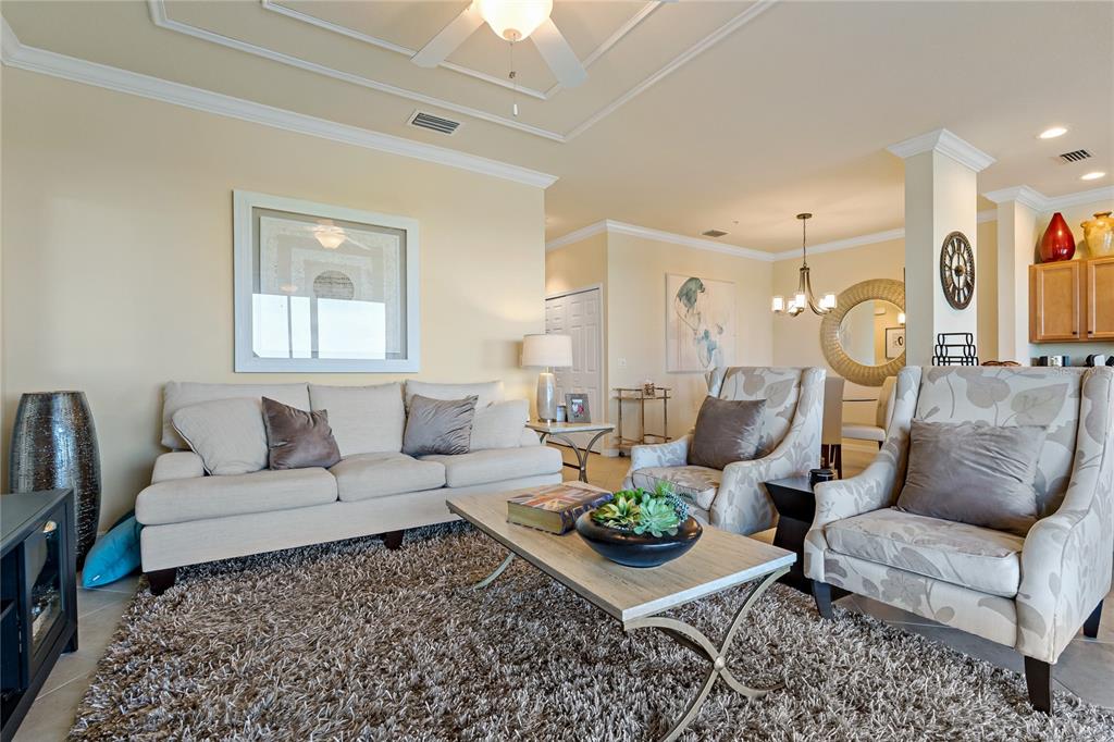 A living room features a beige sofa, two patterned armchairs, and a shaggy area rug — 7015 RIVER HAMMOCK DRIVE UNIT 405, BRADENTON, FL