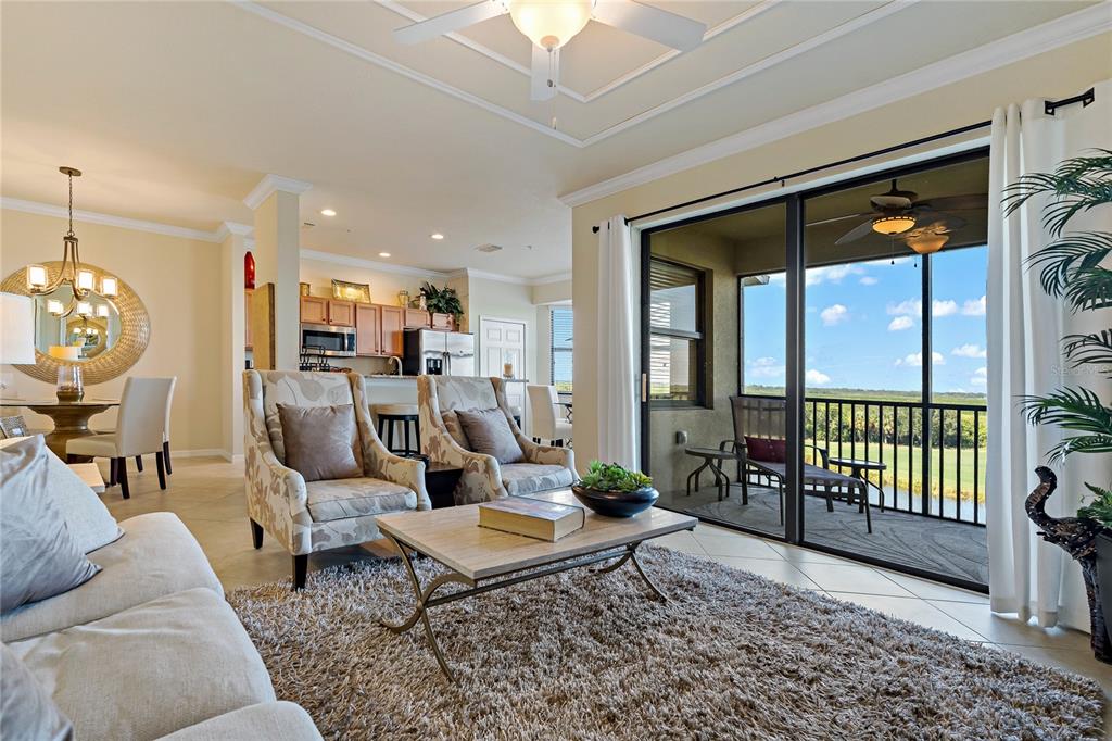 A living room with a shaggy rug, two patterned armchairs, and a sliding door to a balcony — 7015 RIVER HAMMOCK DRIVE UNIT 405, BRADENTON, FL